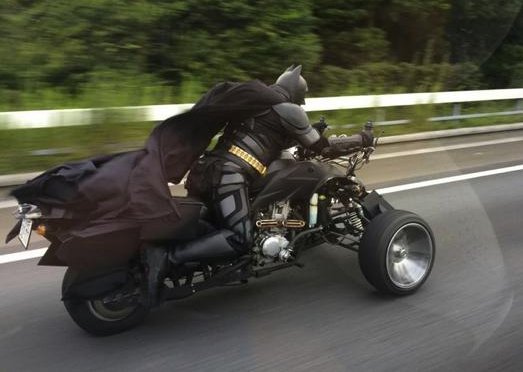 A man riding a motorcycle, dressed as Batman