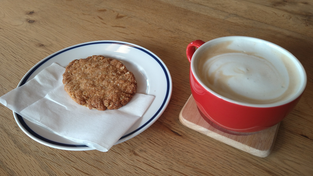 A picture of a Coffee cup and a cookie.