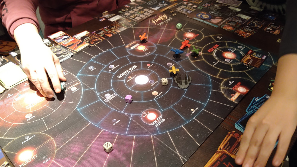 A picture of the Firefly boardgame in progress. The board is a space map with planets and stars, and plastic spaceships represent the players.