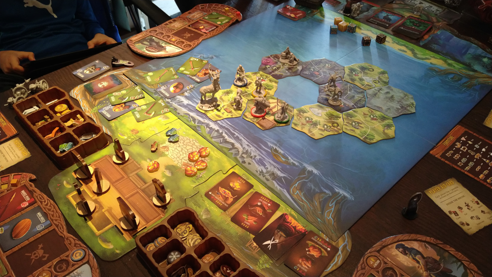 A picture of the Valheim boardgame in progress. There are many miniatures of viking warriors and monsters on top of tiles representing an island in the ocean.