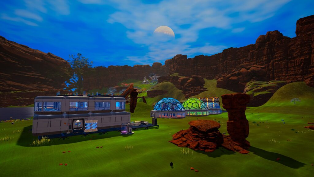 Screenshot of a 3D game, showing a blocky, futuristic-looking base on a green fields among brown mountains, under a blue sky.